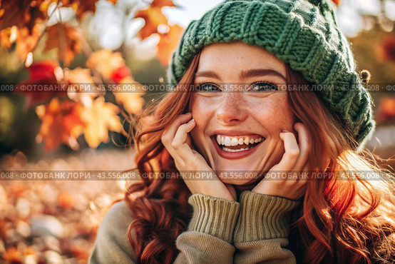Autumn portrait. Close-up of a red-haired young woman with expressive green eyes in a knitted hat and sweater. The girl laughs in the rays of the setting autumn sun. Стоковое AI-изображение, AI-художник Photojuli / Фотобанк Лори