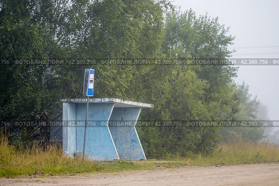 Автобусная остановка в сельской местности. Утренний туман. На автобусной остановке никого нет. Рядом с остановкой установлен дорожный знак. Безлюдная дорога. Окраина села. Стоковое фото, фотограф Андрей Степанов / Фотобанк Лори