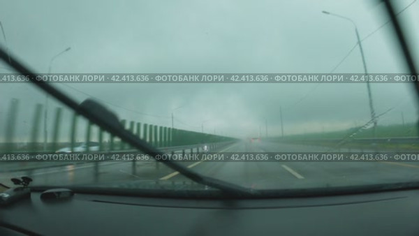 Автомобиль едет по автостраде в дождь. Вид из салона автомобиля. Лобовое стекло покрыто каплями дождя, дворники работают быстро. Плохая видимость. Путешествие на автомобиле в плохую погоду. Стоковое видео, видеограф Воловодов Владимир / Фотобанк Лори
