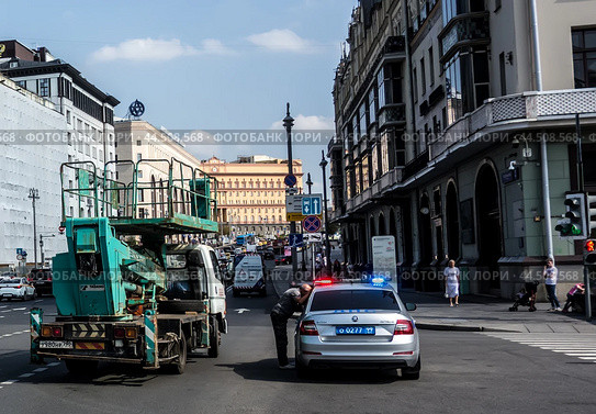 Автовышка Tadano в центре Москвы на Театральной площади остановлена патрульным автомобилем. Водитель вышки вышел из машины и отвечает на вопросы гаишника.(2024)/ A Tadano aerial platform in the center of Moscow on Teatralnaya Square was stopped by a patrol car for violating traffic rules. Редакционное фото, фотограф Iva Noel / Фотобанк Лори