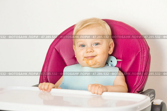 Baby food. The first meal. Feeding the baby. A cute little kid eats vegetables. Healthy food. The child is sitting on a high chair for feeding. Fresh vegetables and fruits. Стоковое фото, фотограф Photojuli / Фотобанк Лори