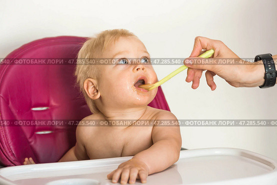 Baby food. The first meal. Feeding the baby. A cute little kid eats vegetables. Healthy food. The child is sitting on a high chair for feeding. Fresh vegetables and fruits. Стоковое фото, фотограф Photojuli / Фотобанк Лори