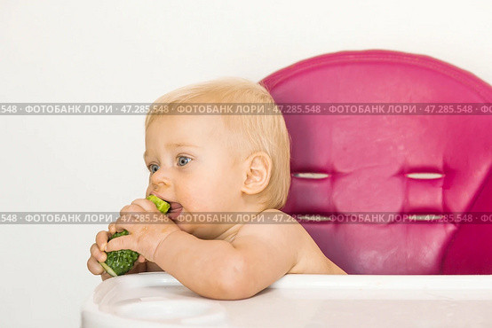 Baby food. The first meal. Feeding the baby. A cute little kid eats vegetables. Healthy food. The child is sitting on a high chair for feeding. Fresh vegetables and fruits. Стоковое фото, фотограф Photojuli / Фотобанк Лори