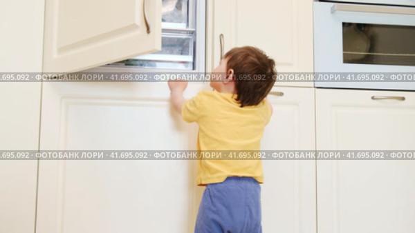 Baby takes a risk and opens the freezer door to grab some food. Always make sure to close the fridge door properly to avoid any accidents. Kid aged about two years (one year ten months) Стоковое видео, видеограф Андрей Журавлев / Фотобанк Лори