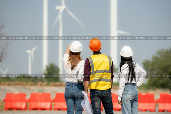 Back view of group engineers and architects on construction site with wind turbines in background. Стоковое фото, агентство Ingram Publishing / Фотобанк Лори