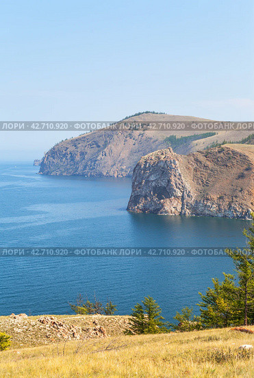 Baikal Lake in August misty day. Beautiful calm landscape of Olkhon Island. View from Cape Sagan-Khushun to rocky Cape Damnuriy. Natural background. Summer holidays and outdoor recreation. Стоковое фото, фотограф Виктория Катьянова / Фотобанк Лори