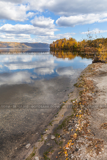Baikal Lake in September sunny day. View from the shore with yellow fallen leaves to natural landmark - Cape Shamansky. Beautiful autumn landscape with reflective clouds in blue water. Стоковое фото, фотограф Виктория Катьянова / Фотобанк Лори