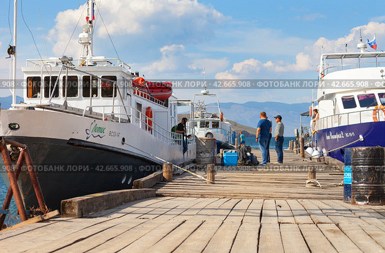 BAIKAL LAKE, OLKHON ISLAND, SAKHYURTA VILLAGE, IRKUTSK REGION, RUSSIA - August 14, 2023: A group of tourists going on a water cruise on a ship around Baikal Lake on a sunny summer day. Редакционное фото, фотограф Виктория Катьянова / Фотобанк Лори