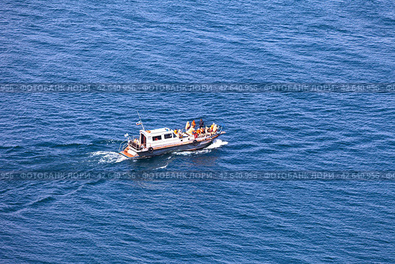 BAIKAL LAKE, OLKHON ISLAND, USYK VILLAGE, IRKUTSK REGION, RUSSIA - August 15, 2023: Top view of group of tourists travels along Small Sea on pleasure boat around Olkhon Island on summer day. Редакционное фото, фотограф Виктория Катьянова / Фотобанк Лори