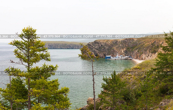 Baikal Lake on hot foggy summer day. Tourists travel on pleasure boat along Small Sea and sail into cozy sandy bay of Olkhon Island for rest and fishing. Summer travels and outdoor recreation. Стоковое фото, фотограф Виктория Катьянова / Фотобанк Лори