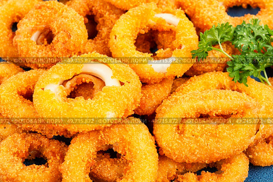 Baked breaded calamari rings served with lime. Food background.. Deep fried squid rings, close up. Стоковое фото, агентство Ingram Publishing / Фотобанк Лори
