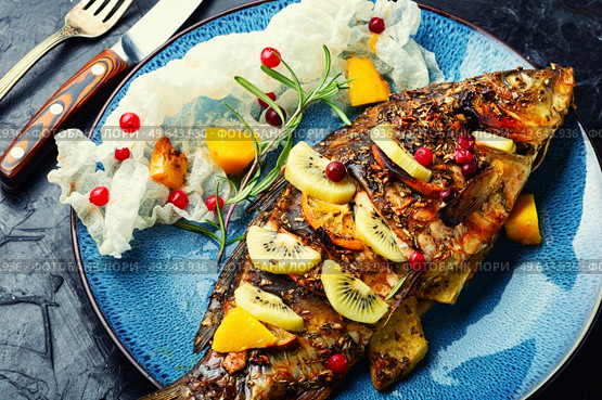 Baked fish carp with fruits, berries and spices.. Tasty crucian fried with kiwi and mango. Стоковое фото, агентство Ingram Publishing / Фотобанк Лори