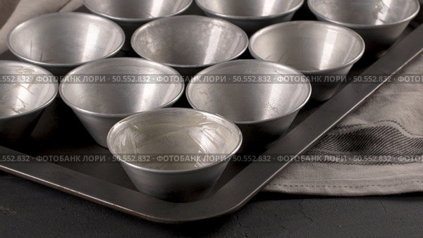 Baking forms smeared with butter prepared to egg tarts, traditional portuguese dessert, pastel de nata, custard tarts home production. Стоковое фото, агентство Ingram Publishing / Фотобанк Лори
