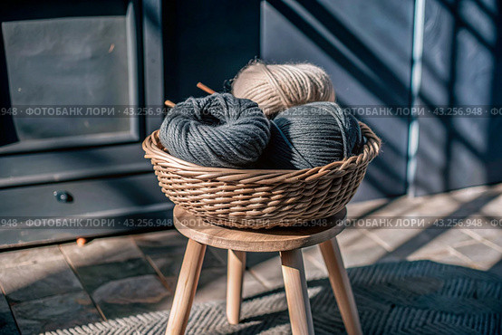 Balls of yarn in a wicker basket on a wooden stool. Needlework, textiles, knitting. Winter season, small business, handmade clothes. Стоковое AI-изображение, AI-художник Photojuli / Фотобанк Лори