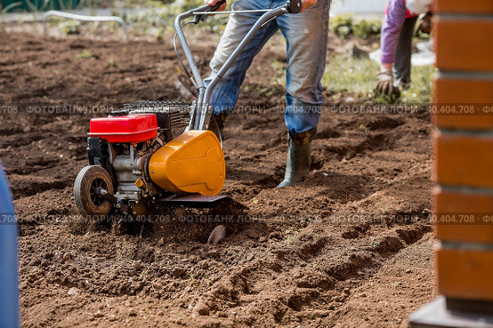 Banner. Man Farmer plows the land with a cultivator. Agricultural machinery: cultivator for tillage in the garden,motor cultivator. Стоковое фото, фотограф Photojuli / Фотобанк Лори