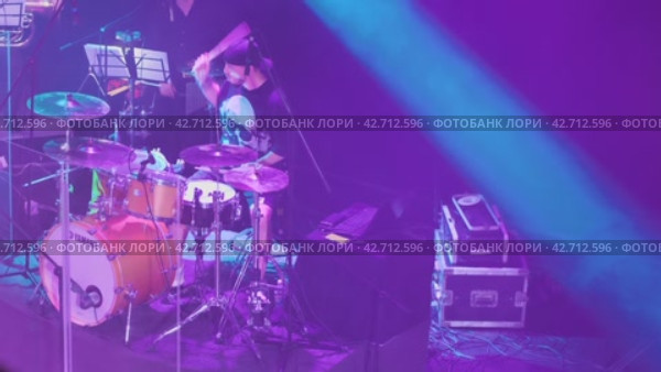 Барабанщик на сцене играет на барабанной установке Yamaha. Над ним висит микрофон, мужчина поет. Разноцветное освещение сцены. Россия, 5 июня 2023 года. Редакционное видео, видеограф Воловодов Владимир / Фотобанк Лори