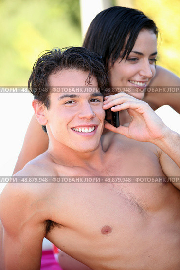 bare-chested boy phoning with girlfriend by his side. Стоковое фото, агентство Ingram Publishing / Фотобанк Лори