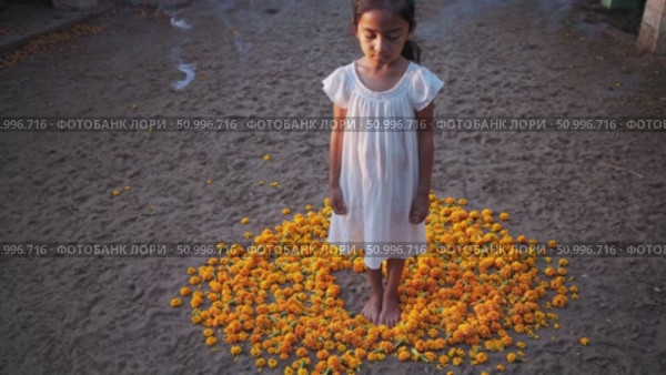 Barefoot woman wearing white dress meditating within circular arrangement of vibrant marigold flowers, surrounded by softly swirling incense smoke. Стоковое AI-видео, аниматор Данил Руденко / Фотобанк Лори
