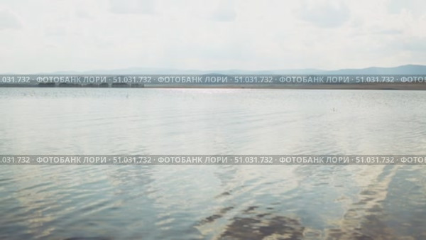 Bashkortostan, Russian Federation - August 07, 2025: Aerial view of tranquil lake reflecting clouds and mountains, showcasing serene landscape with lush greenery and open sky. Редакционное видео, видеограф Ирина Ручушкина / Фотобанк Лори