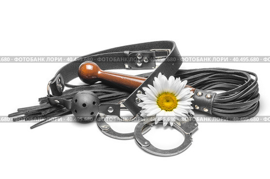 Bdsm black leather gag with handcuffs and a yellow daisy flower on a white background. Стоковое фото, фотограф Артем Курутин / Фотобанк Лори