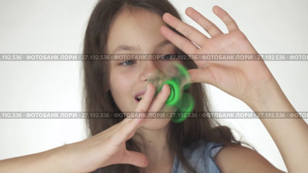 Beautiful cheerful teen girl playing with green fidget spinner on white background stock footage video. Стоковое видео, видеограф Юлия Машкова / Фотобанк Лори