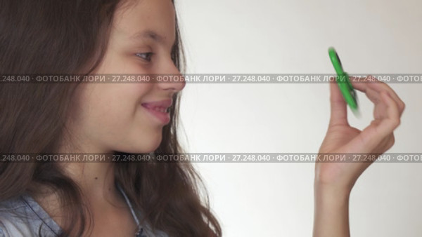 Beautiful cheerful teen girl playing with green fidget spinner on white background stock footage video. Стоковое видео, видеограф Юлия Машкова / Фотобанк Лори
