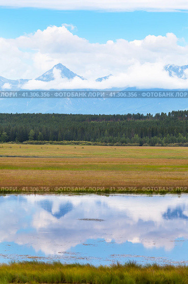 Beautiful landscape of foothill valley in early autumn. On rocky mountains there are low cumulus clouds, behind river with reflection of mountain there is yellowed meadow. Natural background. Стоковое фото, фотограф Виктория Катьянова / Фотобанк Лори
