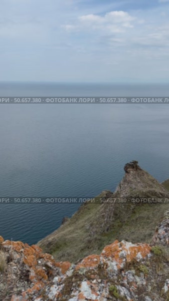 Beautiful panoramic view of rocky coast of Baikal Lake at summer day. Vertical video of lake from the height of the rocks. Summer travel and outdoor activity. Стоковое видео, видеограф Виктория Катьянова / Фотобанк Лори