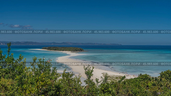Beautiful tropical postcard landscape. A green island in the aquamarine ocean. Silhouettes of people on a winding sandbar. Boats near the shore. Green vegetation in the foreground. The blue sky. Стоковое фото, фотограф Вера Ивановна Кубарева / Фотобанк Лори
