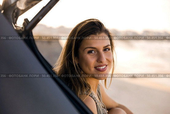 Beautiful woman sitting in the trunk of a car near a beach and smilling. Стоковое фото, агентство Ingram Publishing / Фотобанк Лори