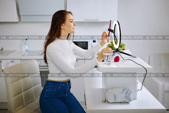 Beauty blogger uses ring light with cell phone holder during live stream at home. Стоковое фото, фотограф Владимир Григорьев / Фотобанк Лори