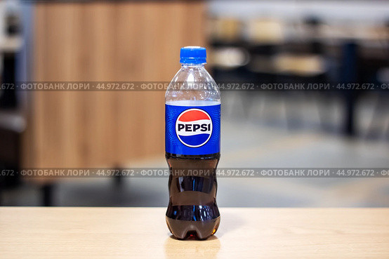 Belarus, Minsk - 18 july, 2024: A plastic bottle containing pepsi rests on a rustic wooden table. Редакционное фото, фотограф Аксенова Вера / Фотобанк Лори