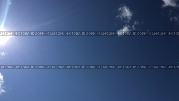 Белые облака быстро плывут по небу. По голубому небу быстро плывут пушистые белые кучевые облака. Облака на лету меняют форму и размер. Солнце появляется на небе и движется вправо. Стоковое видео, видеограф Andrew_Swarga / Фотобанк Лори