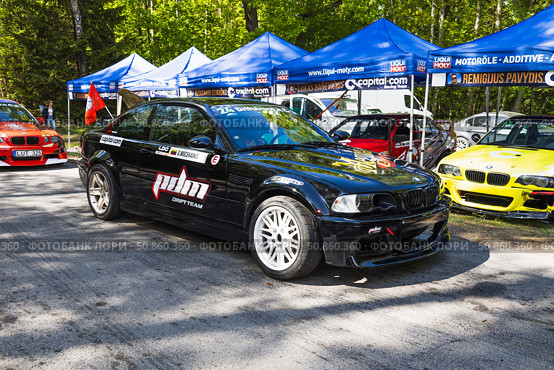 Black BMW drift car with sponsor livery in sunny paddock. Alytus, Lithuania, 25 May 2025. Редакционное фото, фотограф Zydrius Tartenis / Фотобанк Лори