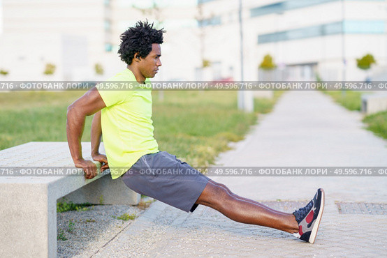 Black man doing triceps dip exercise on city street bench. Fitness, sport, exercising, training and people concept. Black man doing triceps dip exercise on city street bench. Стоковое фото, агентство Ingram Publishing / Фотобанк Лори