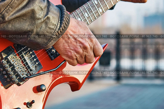 BLAGOVESHCHENSK, RUSSIA - MAY 01, 2022: Guitarist plays the electric guitar on the city embankment. Labor Day. Редакционное фото, фотограф Алексей Игнатов / Фотобанк Лори