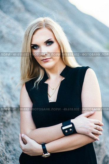 blonde girl in a black trouser suit with blue eyes on the background of a granite quarry from gray rubble. Стоковое фото, агентство Ingram Publishing / Фотобанк Лори