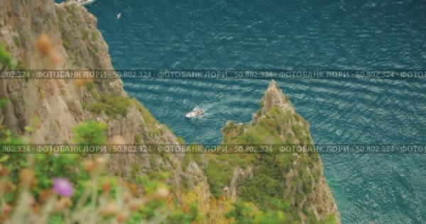 Boat cruising near pointed cliff edge over deep blue sea in summer Capri Italy. Стоковое видео, видеограф Igor Tichonow / Фотобанк Лори