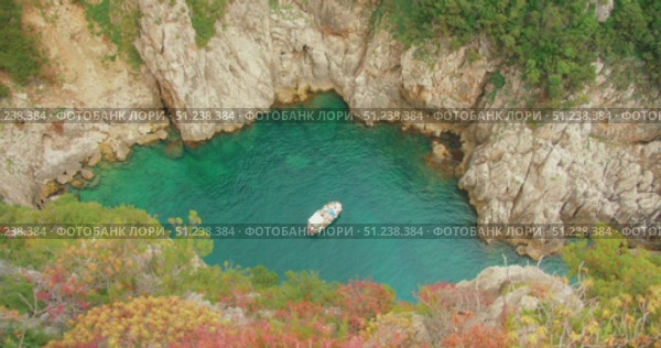 Boat floating in secluded turquoise cove with rocky walls during Capri tour. Стоковое видео, видеограф Ольга Сухарева / Фотобанк Лори
