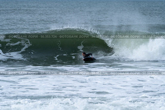 Bodyboarder performing a tube trick surfing ocean wavesurfing ocean wave on a cloudy winter day. Стоковое фото, агентство Ingram Publishing / Фотобанк Лори