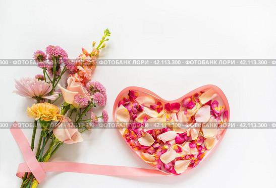 Bouquet of fresh flowers with roses, carnations and chrysanthemums with pink ribbon in shape of heart filled with rose petals. Romantic greetings on Valentine's Day, March 8 or Birthday. Стоковое фото, фотограф Виктория Катьянова / Фотобанк Лори
