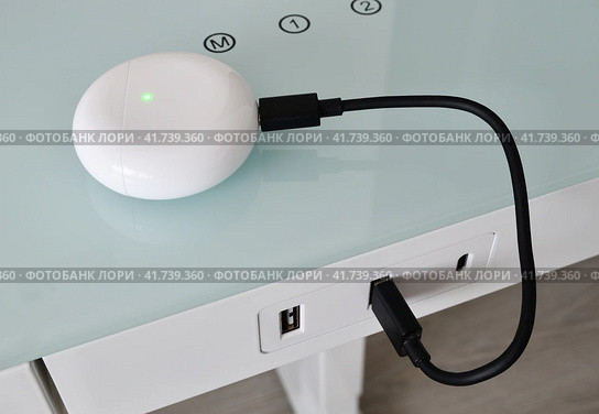 Box for wireless headphones is charged from the USB table. Стоковое фото, фотограф Володина Ольга / Фотобанк Лори