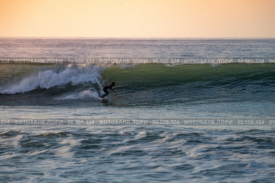 Brave teenager making tricks on the rough sea during sunset. Стоковое фото, агентство Ingram Publishing / Фотобанк Лори