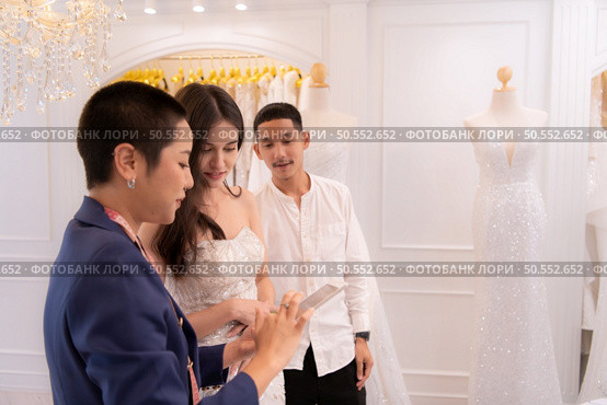 Bridal gown designers and tailors measure the size of the gown against the bride’s figure when she comes to try on the gown in order to make it perfect and ready to wear on the wedding day. Стоковое фото, агентство Ingram Publishing / Фотобанк Лори