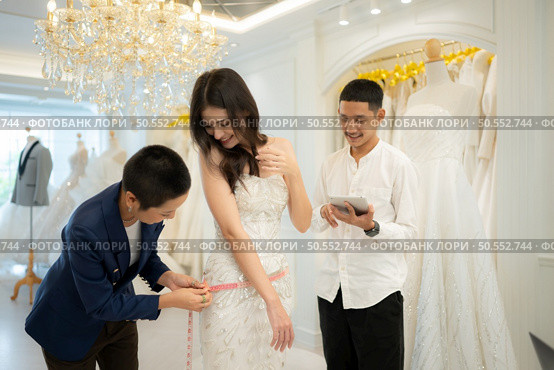 Bridal gown designers and tailors measure the size of the gown against the bride’s figure when she comes to try on the gown in order to make it perfect and ready to wear on the wedding day. Стоковое фото, агентство Ingram Publishing / Фотобанк Лори