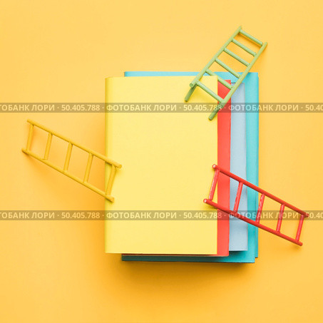 bright ladders stack colorful blank books yellow background. Стоковое фото, агентство Ingram Publishing / Фотобанк Лори