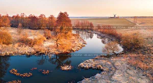 Bright sunrise over wild curved river aerial view. River landscape in sunlight from above. Belarus. Sunrise at the spring fields. Traditional windmill in morning light. . Стоковое фото, агентство Ingram Publishing / Фотобанк Лори