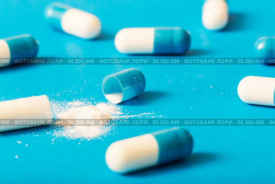 broken capsule with white powder blue background. Стоковое фото, агентство Ingram Publishing / Фотобанк Лори
