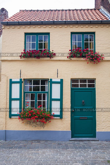 Brugge, Belgium. Old town building with door and flowers in windows.. Old town building with door and flowers in windows. Стоковое фото, агентство Ingram Publishing / Фотобанк Лори