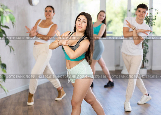 Brunette teenage girl practicing vigorous dance with group in studio. Стоковое фото, фотограф Яков Филимонов / Фотобанк Лори